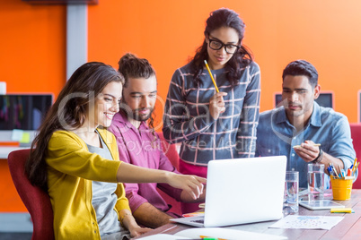 Smiling graphic designers discussing over laptop in meeting