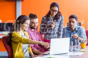 Smiling graphic designers discussing over laptop in meeting