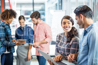 Male and female executives having discussion over laptop