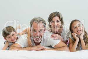 Portrait of smiling family lying on bed in bedroom