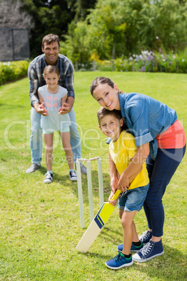 Family playing cricket in park