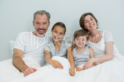 Happy family lying together on bed in bedroom at home