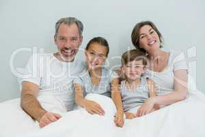 Happy family lying together on bed in bedroom at home