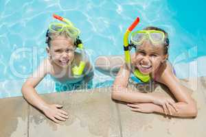 Smiling boy and girl relaxing on the side of swimming pool