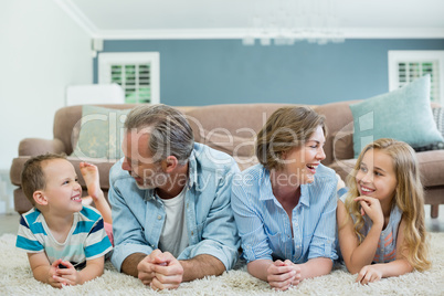 Smiling family lying together on carpet in living room