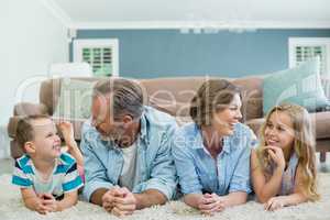 Smiling family lying together on carpet in living room