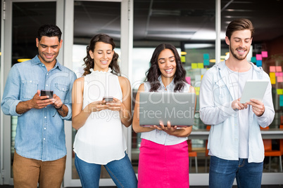 Smiling executives using mobile phone, laptop and digital tablet