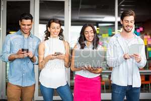 Smiling executives using mobile phone, laptop and digital tablet