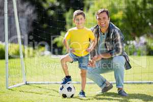 Father and son with football in the park on a sunny day