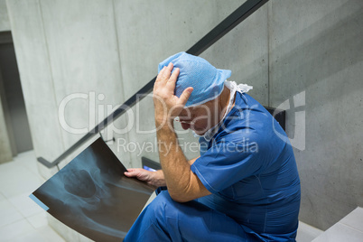 Tensed male surgeon examine x-ray on staircase