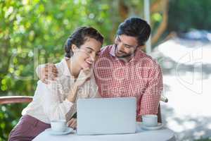 Couple smiling while using laptop