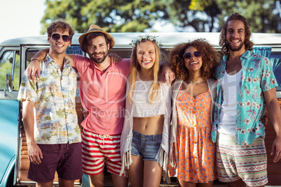 Group of happy friends standing together near campervan