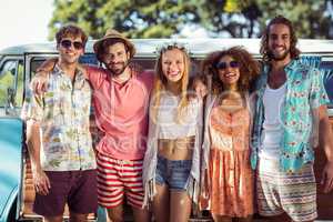 Group of happy friends standing together near campervan