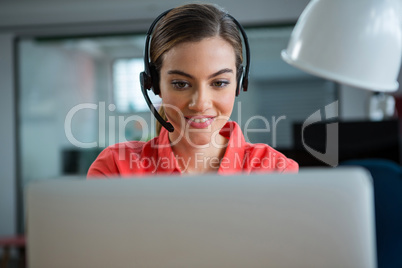 Smiling female executive working on her laptop while calling