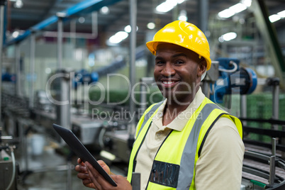 Smiling factory worker using a digital tablet in the factory