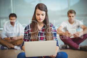 Business executives sitting on floor and using laptop