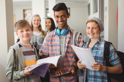 Students standing with notebook and digital tablet in corridor