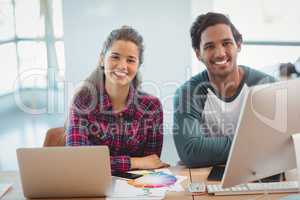 Male and female graphic designers sitting at desk