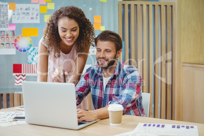 Graphic designers discussing over laptop