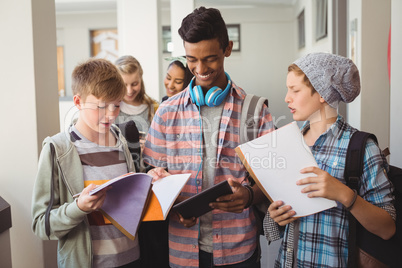 Students standing with notebook and digital tablet in corridor