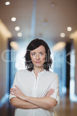 Portrait of female executive standing with arms crossed in corridor