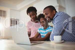 Parents and daughter using laptop in kitchen