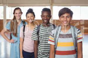 Portrait of happy students standing with schoolbags in campus