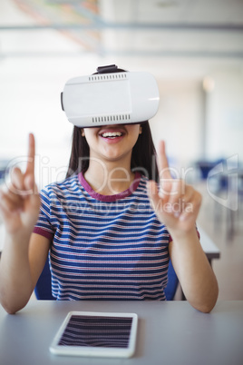 Schoolgirl using virtual reality headset in classroom