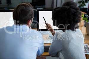 Man and woman discussing over desktop pc