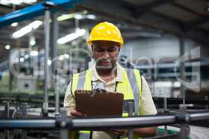 Factory worker looking at clipboard in factory