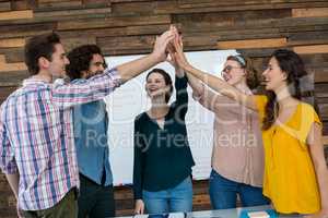 Business executives giving high five in office