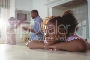 Sad girl listening to her parents arguing in kitchen