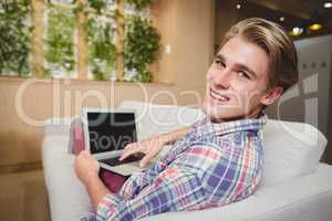 Portrait of male business executive relaxing on sofa and using laptop