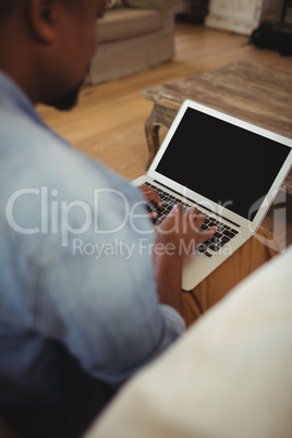 Man sitting and using laptop in living room