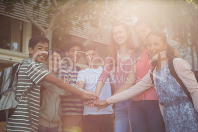 Happy school kids forming hand stack in campus at school