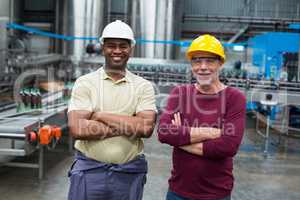 Two factory workers standing with their arms crossed in drinks production plant