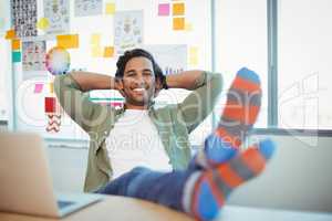 Male graphic designer relaxing with feet up at desk