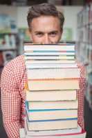 Portrait of school teacher holding stack of books in library