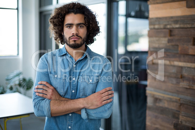 Sad business executive standing with arms crossed in office