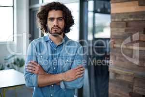 Sad business executive standing with arms crossed in office