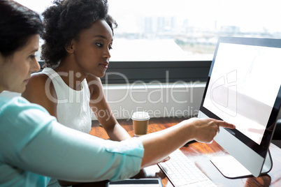 Female graphic designer pointing to desktop pc