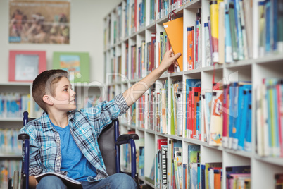 Disabled schoolboy selecting book in library