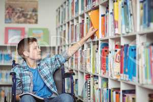 Disabled schoolboy selecting book in library