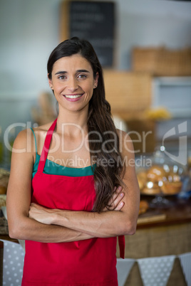 Portrait of female staff standing with arms crossed at counter