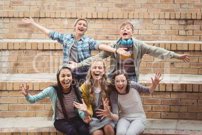 Portrait of smiling school students sitting on staircase having fun in campus