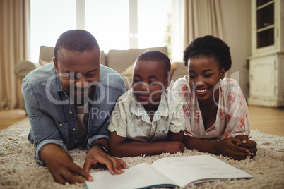 Parents and son reading a book while lying on a rug