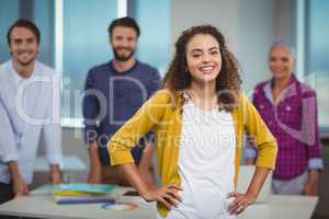 Portrait of smiling graphic designer standing with her colleagues in background