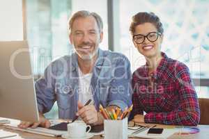 Portrait of male graphic designer sitting with coworker in office