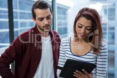 Man and woman discussing over digital tablet