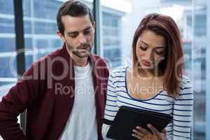 Man and woman discussing over digital tablet